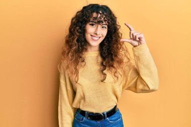 Gündelik kıyafetler giyen, gülümseyen, kendine güvenen, el hareketi yapan, parmaklarıyla işaret yapan ve kameraya bakan genç İspanyol kız. ölçüm kavramı. 