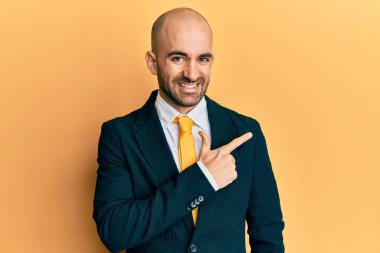 Genç İspanyol bir adam iş elbisesi giyiyor ve neşeli bir kravat takıyor. Yüzünde mutlu ve doğal bir ifadeyle elleri ve parmaklarıyla yüzünü gösteren bir gülümseme var. 