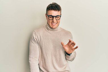 Balıkçı yaka kazak giyen İspanyol genç adam tiksindirici bir ifade takındı. Tiksinti reaksiyonu yüzünden tiksinti ve korku ifadesi takınıyordu.. 