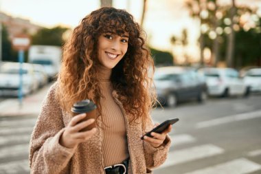 Genç İspanyol kadın akıllı telefon kullanıyor ve şehirde kahve içiyor.