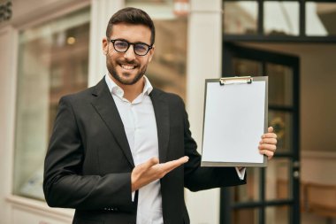 Genç İspanyol işadamı gülümsüyor. Şehirde elinde bir pano var..