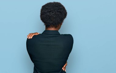 Afro saçlı genç Afrikalı Amerikalı kadın ayakta dikiliyor ve başka tarafa bakıyor.