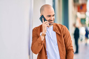 Genç, kel, gülümseyen, mutlu, akıllı telefondan konuşan bir adam..