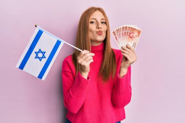 Genç İrlandalı bir kadın İsrail bayrağını tutuyor ve kameraya bakıp öpücüklere bakıyor. aşk ifadesi. 