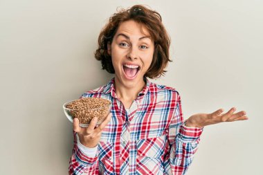 Genç esmer kadın mercimeği fırına verip başarıyı mutlu bir gülümsemeyle kutluyor ve kazanan yüz ifadesi kaldırıyor. 