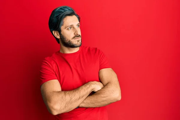 Νεαρός Ισπανός Που Φοράει Κόκκινο Μπλουζάκι Κοιτώντας Στο Πλάι Σταυρωμένα — Φωτογραφία Αρχείου