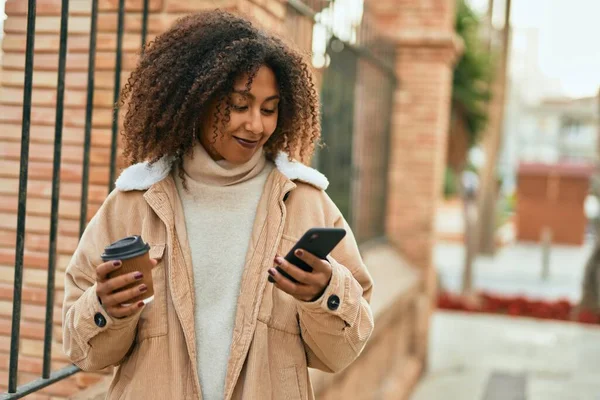 アフリカ系アメリカ人の若い女性が市内でスマートフォンやコーヒーを飲んでいる — ストック写真