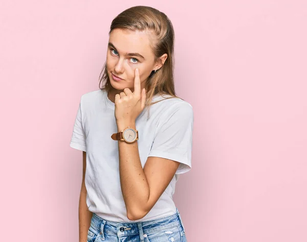 Hermosa Joven Rubia Vistiendo Camiseta Blanca Casual Apuntando Ojo Observándote —  Fotos de Stock