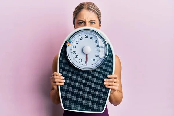 Schöne Blonde Frau Hält Gewichtsmaschine Gewichtsverlust Auszugleichen Skeptisch Und Nervös — Stockfoto