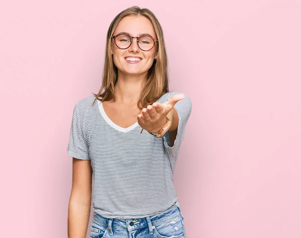 Güzel, genç, sarışın bir kadın. Günlük kıyafetler ve gözlük takıyor. Gülümsüyor, dostça tokalaşıyor. başarılı iş. 