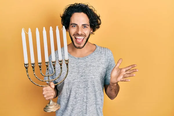 Przystojny Hiszpan Trzyma Menorah Hanukkah Świeca Żydowska Świętowanie Osiągnięcia Uśmiechem — Zdjęcie stockowe