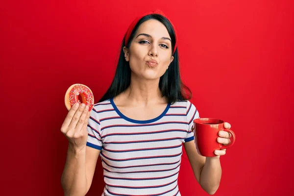 Mujer Hispana Joven Comiendo Donut Bebiendo Café Mirando Cámara Soplando —  Fotos de Stock