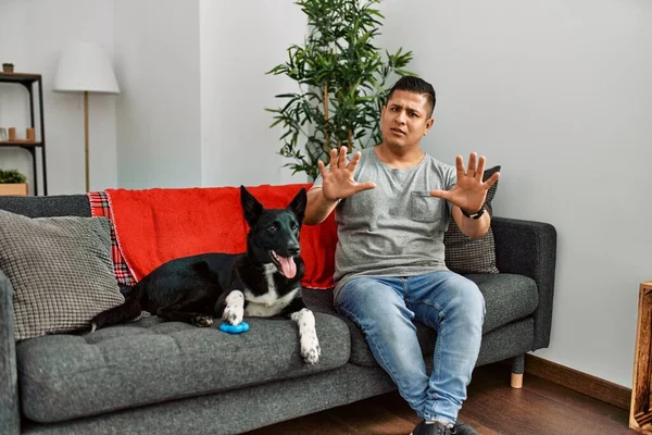 Jovem Latino Homem Cão Sentado Sofá Casa Com Medo Aterrorizado — Fotografia de Stock