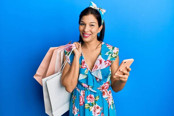 Junge Lateinamerikanische Frau Mit Einkaufstaschen Und Smartphone Zwinkernd Die Kamera — Stockfoto