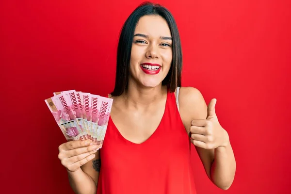 Junges Hispanisches Mädchen Hält 100000 Indonesische Rupiah Und Lächelt Glücklich — Stockfoto