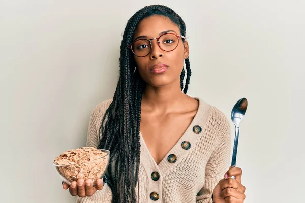 アフリカ系アメリカ人の女性は 顔に深刻な表情でリラックスした健康的な全粒穀物を食べている カメラを見ているだけで — ストック写真