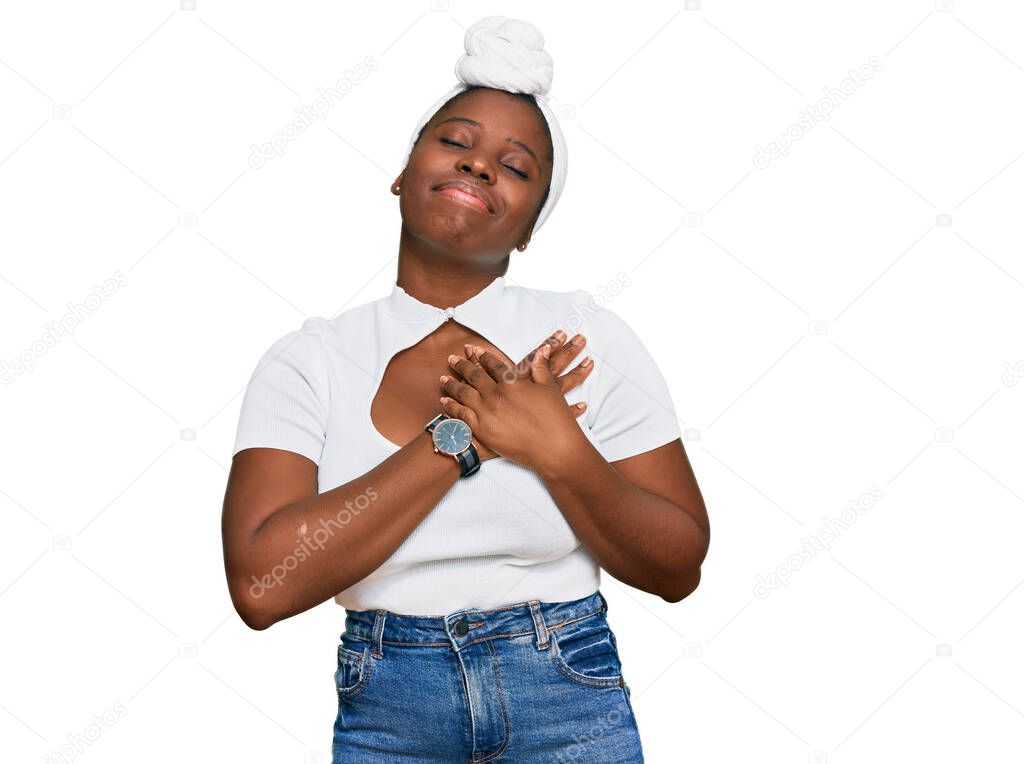 Young african woman with turban wearing hair turban over isolated background smiling with hands on chest with closed eyes and grateful gesture on face. health concept. 