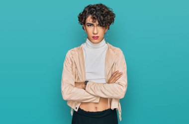 Makyaj yapan yakışıklı bir adam ve kadın kıyafetleri kuşkucu ve gergin. Yüzünde çapraz kollu tasvip etmeyen bir ifade. negatif kişi. 