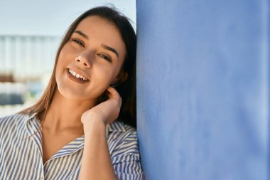 Genç İspanyol kız gülümseyerek şehirde mutlu mesut dikiliyor..