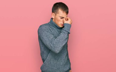 Gündelik kıyafetler giyen genç sarışın adam yorgun burnu ve gözleri ovuşturup yorgunluk ve baş ağrısı hissediyor. Stres ve hüsran kavramı. 