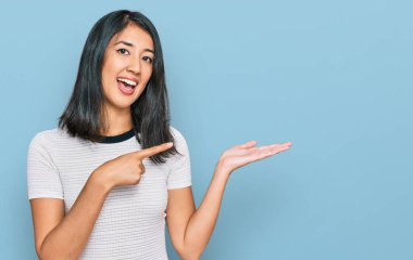 Güzel Asyalı beyaz tişört giyen genç bir kadın kameraya hayret ediyor ve gülümsüyor.. 