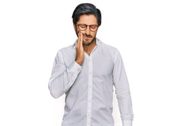 İş gömleği giyen ve gözlüklü genç bir İspanyol diş ağrısı ya da diş hastalığından dolayı ağızlarına acı dolu bir ifadeyle dokunuyor. dişçi 