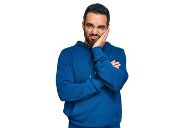 Günlük kıyafetler giyen genç İspanyol adam kollarını kavuşturarak depresyondan sıkılmış ve yorgun görünüyor.. 