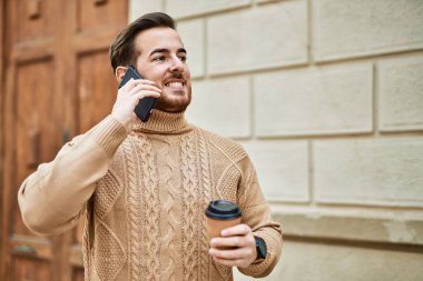 Kafkasyalı genç adam akıllı telefondan konuşuyor. Şehirde kahve içiyor..