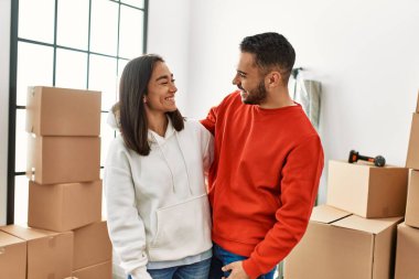 Genç Latin çift gülümsüyor mutlu bir şekilde yeni evinde duruyor.