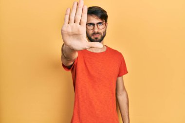 Günlük kıyafetler giyen ve gözlük takan İspanyol genç adam avucunun içi gibi şarkı söylemeyi kesiyor. Yüzünde olumsuz ve ciddi bir jest olan uyarı ifadesi. 