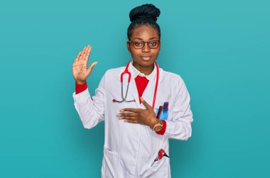 Genç Afro-Amerikan kadın, doktor üniforması ve steteskop giymiş, el pençe divan duran, sadakat yemini eden, 