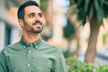 Genç İspanyol adam gülümseyerek şehirde mutlu mesut dikiliyor..