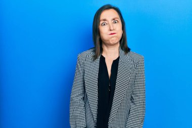 Orta yaşlı İspanyol kadın iş kıyafetleri giyip komik yüzlü yanakları şişiriyor. Havayla şişmiş ağız, çılgın bir ifade.. 