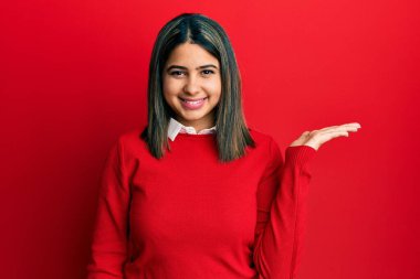 Gündelik kıyafetler giyen, neşeli gülümseyen, avuç içi kameraya bakan genç Latin bir kadın.. 