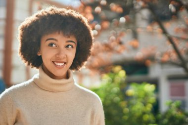 Genç İspanyol kız gülümseyerek şehirde mutlu mesut dikiliyor..