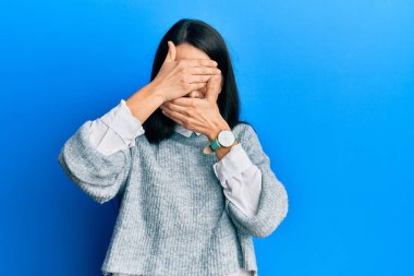 Gündelik kıyafetler giyen genç İspanyol kadın gözlerini ve ağzını elleriyle kapatıyor, şaşırmış ve şok olmuş. duygu gizleme 