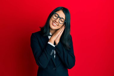 Güzel Asyalı genç kadın iş elbisesi içinde uyur. Yorgun düşler kurar, ellerle poz verir ve gözleri kapalı gülümserdi.. 