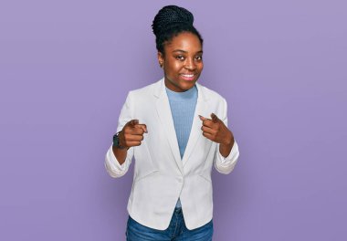 İş kıyafetleri giymiş genç Afro-Amerikalı kadın mutlu ve komik yüzüyle kamerayı işaret ediyor. iyi enerji ve titreşimler. 