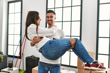 Genç İspanyol bir adam yeni evinde kadını kollarında tutuyor..