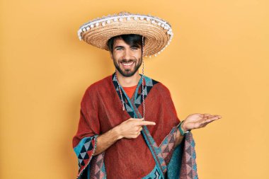 Meksika şapkası tutan genç İspanyol adam kameraya hayret ediyor ve gülümsüyor.. 