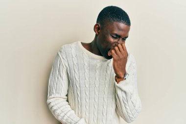 Genç, Afro-Amerikan bir adam günlük giysiler giymiş pis ve iğrenç bir koku alıyor, dayanılmaz bir koku, parmakları burnunda nefesini tutuyor. Kötü kokuyor. 