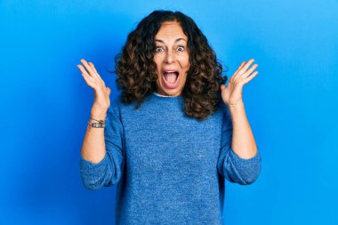 Orta yaşlı İspanyol kadın gündelik giysiler giyip çılgınlığı kutluyor ve başarıya hayret ediyor kolları açık ve gözleri açık heyecanla haykırıyor. Kazanan konsept 