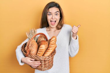 Kafkasyalı genç bir kız elinde hasırdan sepetle başparmağını kaldırmış, ağzı açık gülümsüyor. 