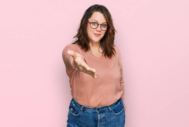 Gündelik kıyafetler ve gözlük takan, neşeli gülümseyen, yardım eli uzatan ve kabul gören genç ve cüsseli bir kadın.. 