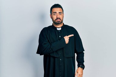 Yakışıklı, sakallı, Katolik rahip cüppeli, endişeli, endişeli ve şaşırmış bir adam. 