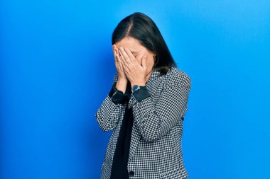 Orta yaşlı İspanyol kadın, ağlarken yüzünü ellerle kapatan üzgün bir ifadeyle iş kıyafetleri giyiyor. depresyon kavramı. 