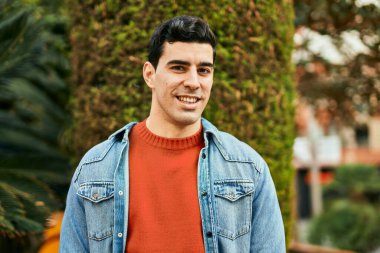 Genç İspanyol adam gülümseyerek şehirde mutlu mesut dikiliyor..