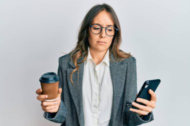 Genç esmer kadın akıllı telefon kullanıyor ve kafası karışık bir şekilde bir fincan kahve içiyor. şüphe kavramı. 