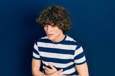 Yakışıklı genç bir adam, eli karnında sıradan çizgili tişört giyiyor çünkü mide bulantısı, acı verici bir hastalık kendini iyi hissetmiyor. Ağrı kavramı. 