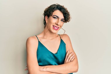 Parti kıyafetleri giymiş genç bir adam kollarını kavuşturup kameraya bakarken gülümsüyor. pozitif kişi. 